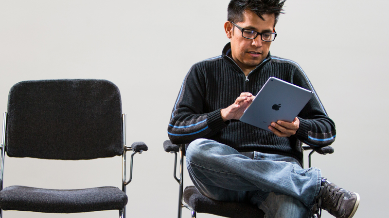 Man sitting cross-legged while using a tablet