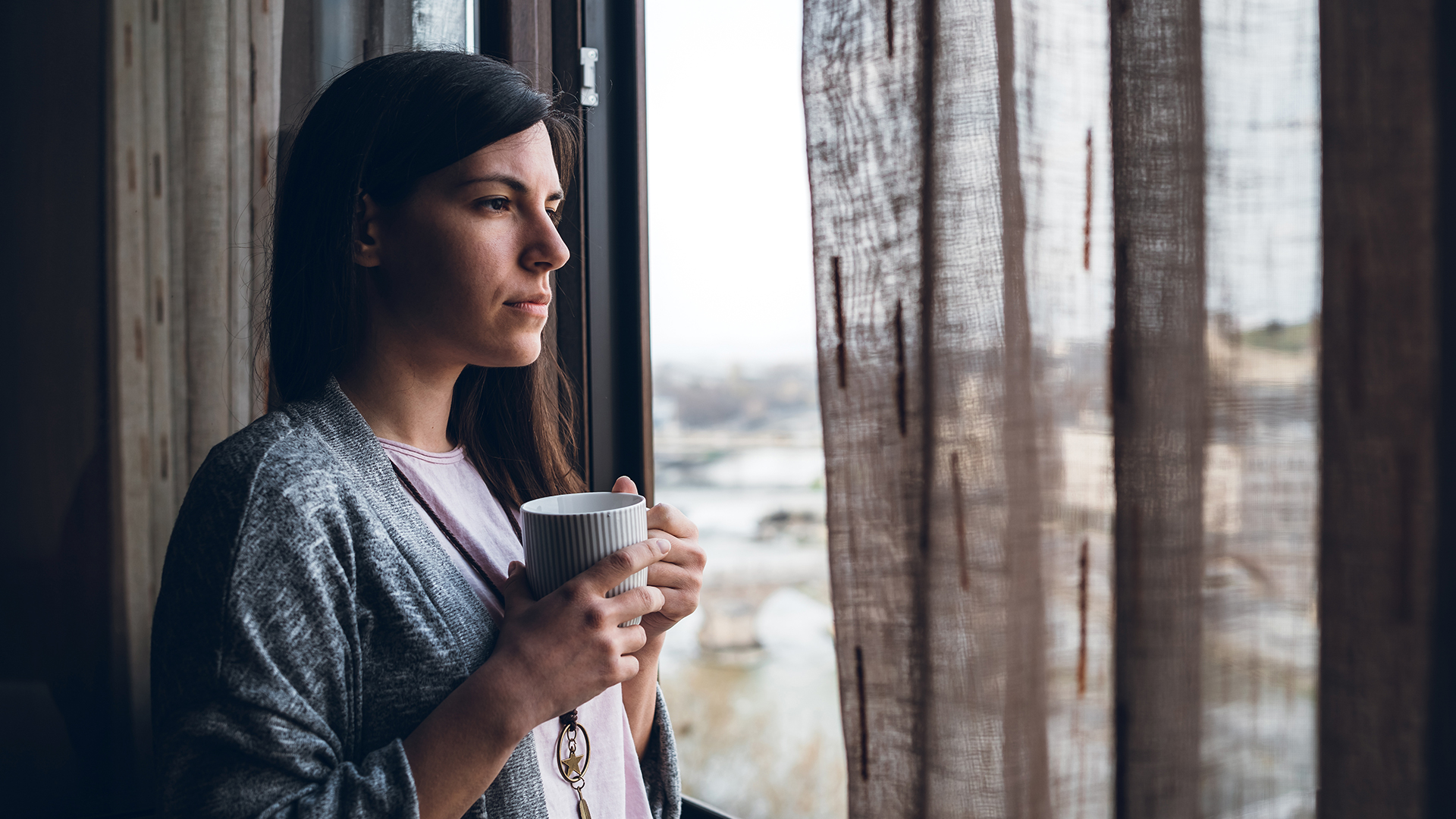 Lady looking out window with coffee | AdvancedMD