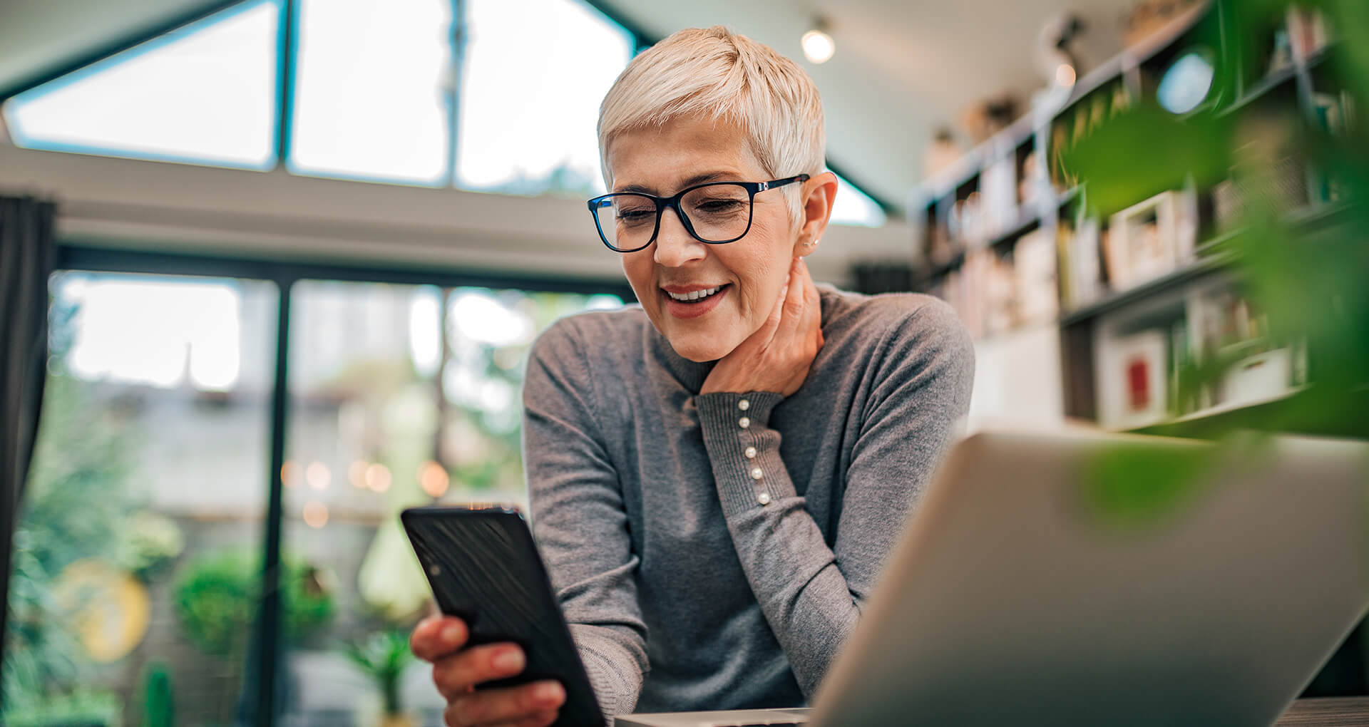 woman looking at phone smiling wearing glasses | AdvancedMD