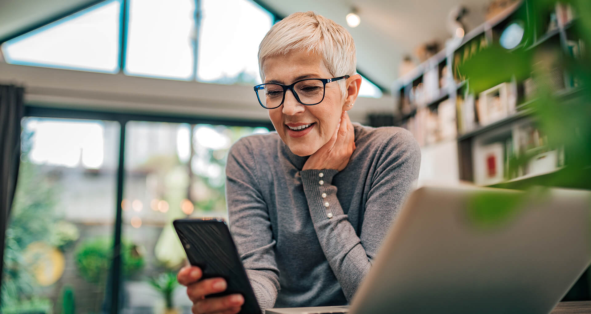 woman looking at phone smiling wearing glasses