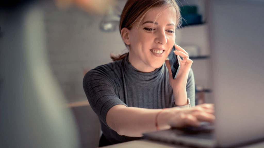 woman talking on the phone while using laptop