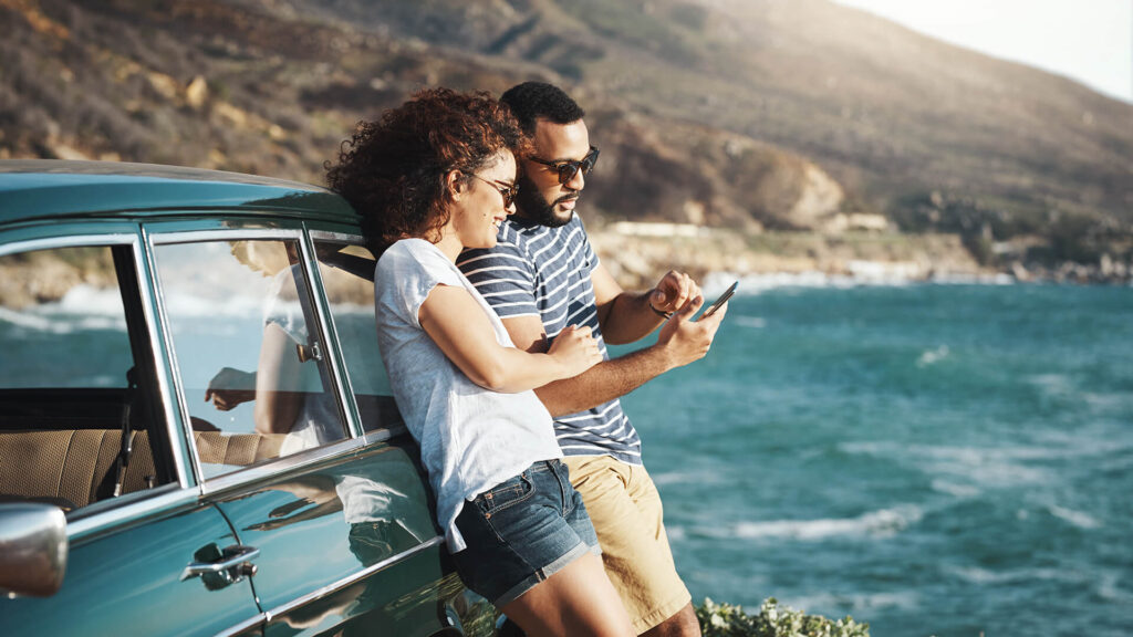 couple leaning on car near the beach
