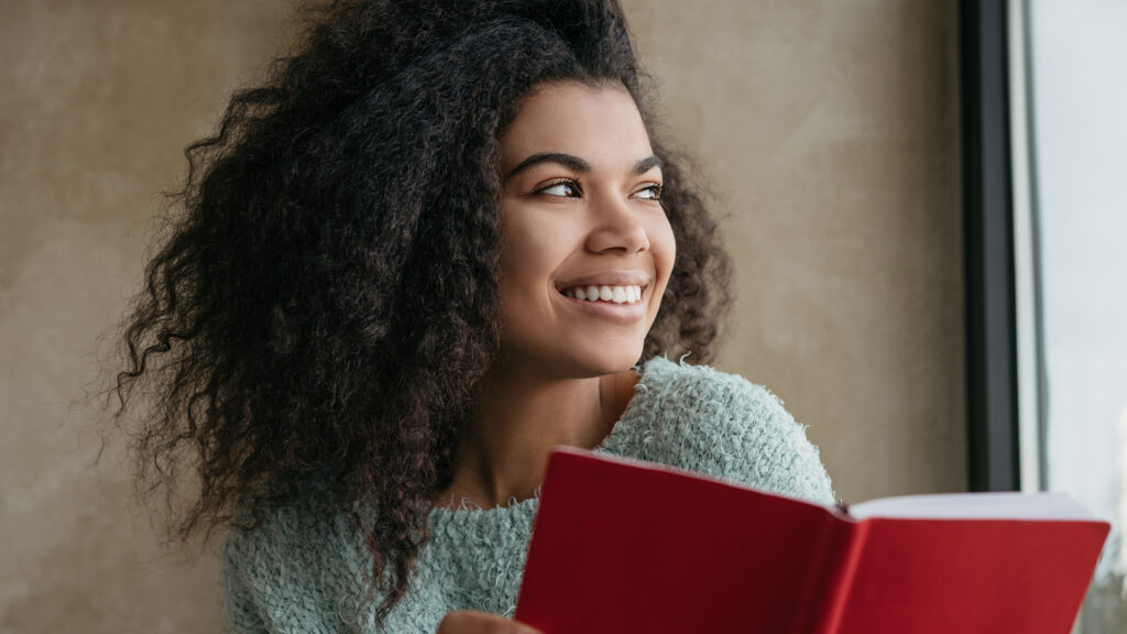 woman holding a red notebook looking outdoors