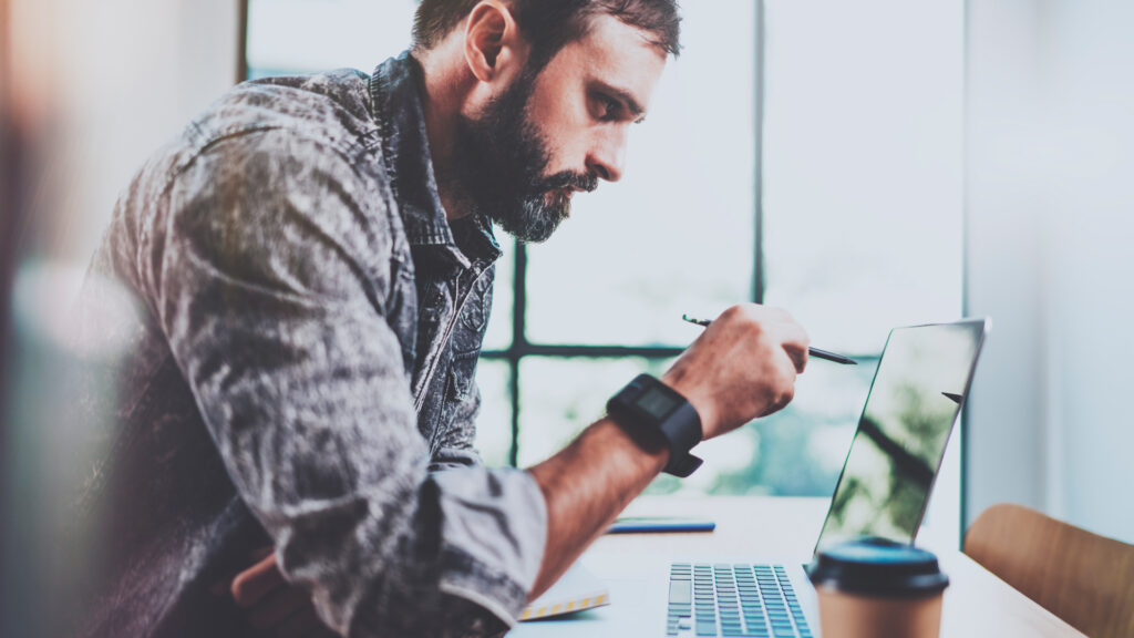 Man pointing a pen on a laptop screen